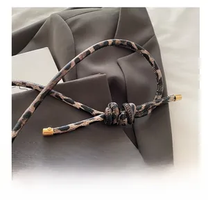 Detail of leopard print bag strap with decorative knots and golden metal ends