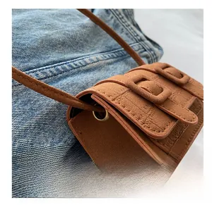 Detailed view of brown crocodile texture mini bag with double flap and metal eyelets