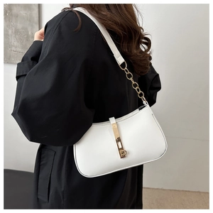 Detail van witte halfmaanvormige tas met gouden ketting op een zwarte jas