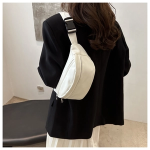 Minimalist white leather chest bag with silver double zippers worn over a black blazer