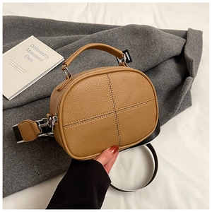 Detail of tan pebble leather pillow bag featuring cross stitching and striped strap