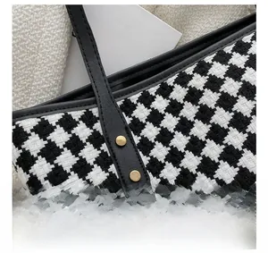 Detail of houndstooth tote bag showing fine stitching and gold rivet accents