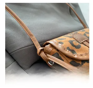 Close-up of leopard print crossbody bag showing fine stitching and horn buckle detail