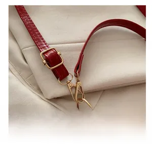 Detail of red leather bag showing the adjustable golden metal buckle and strap hook