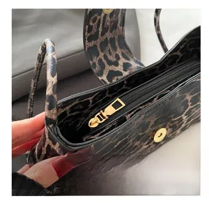 Close-up of leopard print bag featuring gold magnetic snap and smooth zipper detail