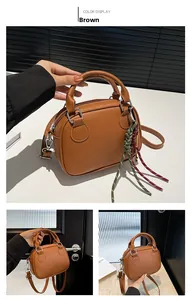 Close-up of brown matte leather bowling bag with dual zipper and woven rope detail