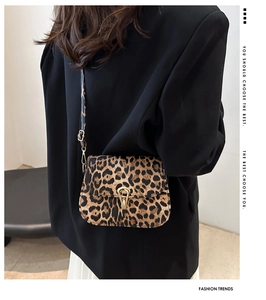 Detail of leopard print saddle bag featuring a gold horseshoe clasp and slim black strap