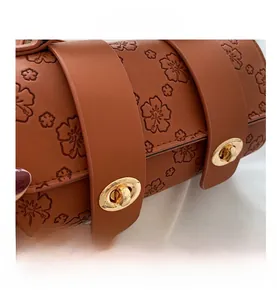 Close-up of caramel brown leather Boston bag with embossed flowers and gold metal locks