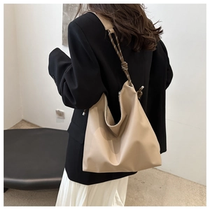 Detail of minimalist beige tote bag with a unique woven rope shoulder strap on a model
