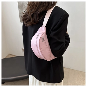 Detail of pink canvas chest bag featuring dual zippers and adjustable padded strap