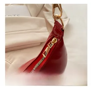 Detail of smooth gold-tone metal zipper and hook on a red wax leather shoulder bag