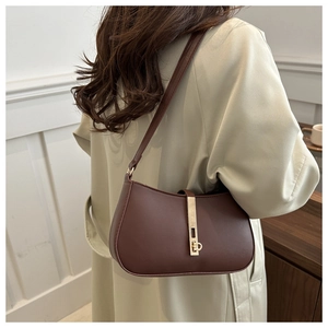 Sac à bandoulière marron foncé avec fermoir doré porté par un mannequin en intérieur