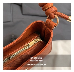 Macro detail of high-quality gold zipper and snake-textured orange leather on a handbag