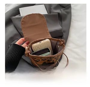 Detail showing the internal capacity of a leopard print canvas bag with phone and wallet