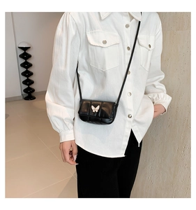Gros plan du mini sac bandoulière matelassé noir avec boucle papillon blanche élégante