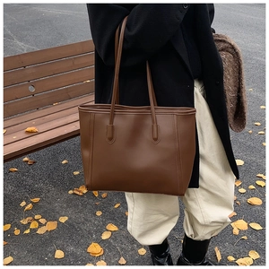 Detail of a large vintage dark brown tote bag on a model in an autumn outdoor setting