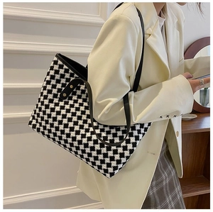 Side view of a houndstooth tote bag with leather straps on a model in a minimalist room