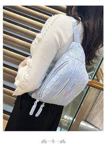 Close-up of light blue corduroy dumpling bag with wavy embroidery and woven zipper pulls