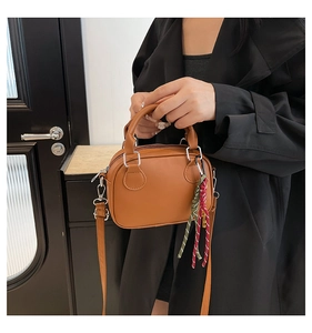 Detail of a brown PU leather bowling bag showing silver hardware and woven pendant