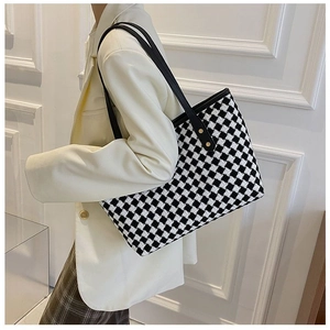 Checkerboard pattern tote bag shown on shoulder with elegant black leather straps
