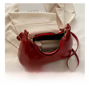 Detail view of red patent leather shoulder bag showing spacious interior and golden hardware