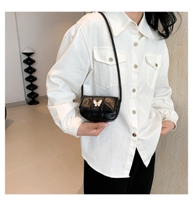 Détail du mini sac bandoulière noir matelassé avec un fermoir papillon doré champagne