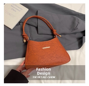 Detail of caramel shoulder bag with lace texture and woven knot handle design