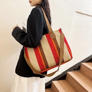 Striped canvas tote bag with multi-color vertical patterns and brown shoulder straps