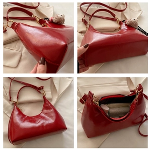 Detailed view of glossy red hobo bag with gold hardware and plush doll pendant