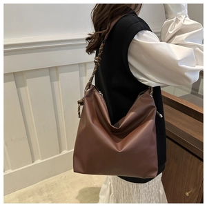 Detail of dark brown leather hobo bag with woven strap and knot detail on model
