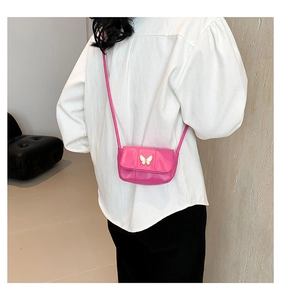Vue détaillée d'un mini sac bandoulière rose avec un ornement papillon blanc porté