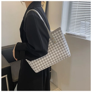 Detail of grey houndstooth tote bag featuring premium leather straps and metal rivets