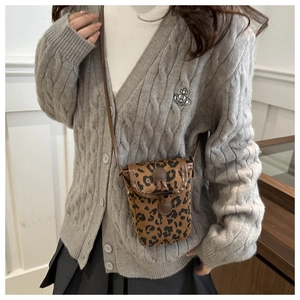 Détail du sac bandoulière léopard en daim avec fermoir en bois sur un pull en maille grise