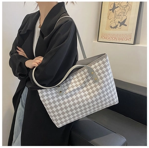 Detail of grey houndstooth tote bag featuring textured tweed fabric and leather handles
