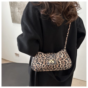 Detail of leopard print crossbody bag with gold bow clasp on a model's shoulder