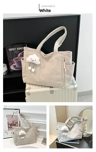 Detail of white corduroy tote bag with plush cloud charm and side pocket texture