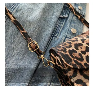 Close-up of golden metal buckle and shoulder strap on leopard print crossbody bag
