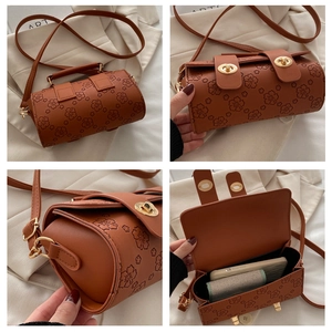 Detailed views of brown cherry blossom embossed cylindrical bag with gold turn-lock