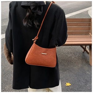 Close-up of caramel brown shoulder bag with lace floral embossing and knotted strap detail