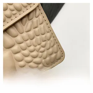 Close-up of premium beige faux crocodile leather texture and fine stitching detail