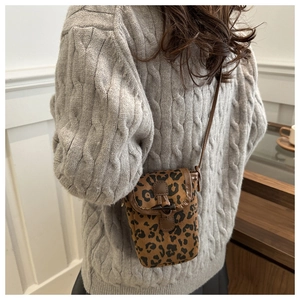 Détail d'un mini sac bandoulière léopard en daim avec bordure cuir et boucle en corne