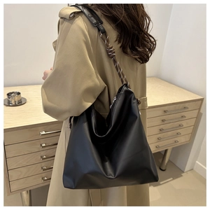 Detail of black tote bag featuring a woven rope handle and sleek silver metal zipper