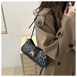 Detailed view of leopard print underarm bag featuring a gold bow buckle on a beige trench coat