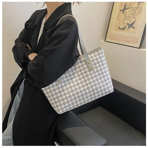 Detail of grey houndstooth tote bag with gold rivets and leather handles on shoulder