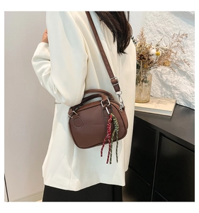 Brown retro bowling bag with woven charm shown as a crossbody on a model in a home setting
