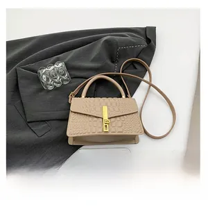 Close-up of beige crocodile embossed handbag with golden lock and detachable strap