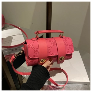 Close-up of pink cylinder bag featuring embossed floral patterns and gold twist lock