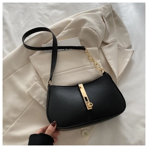 Gros plan sur un sac sous le bras en cuir mat noir avec boucle dorée et chaîne