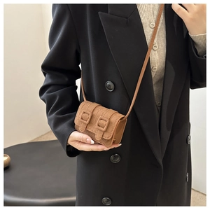 Detail view of a vintage dark brown mini crossbody bag with textured leather and square buckles