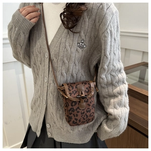 Mini sac bandoulière léopard pour téléphone porté par un mannequin avec finitions en cuir